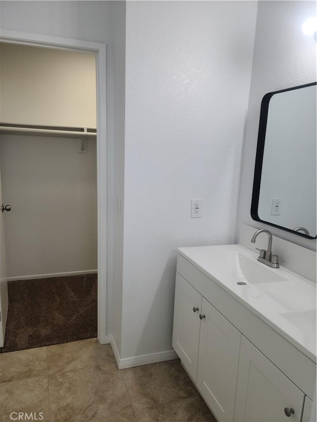 bathroom featuring a spacious closet, vanity, and baseboards