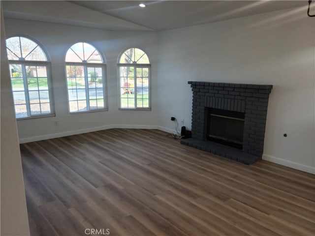 unfurnished living room with recessed lighting, a brick fireplace, baseboards, and wood finished floors