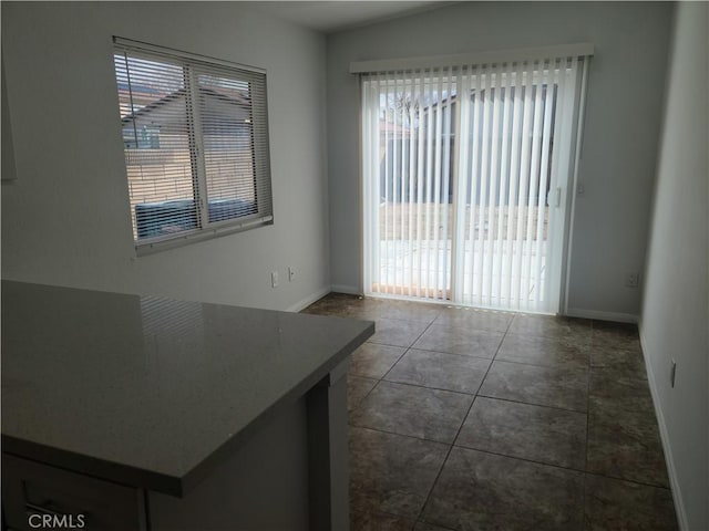 interior space featuring baseboards and dark tile patterned floors