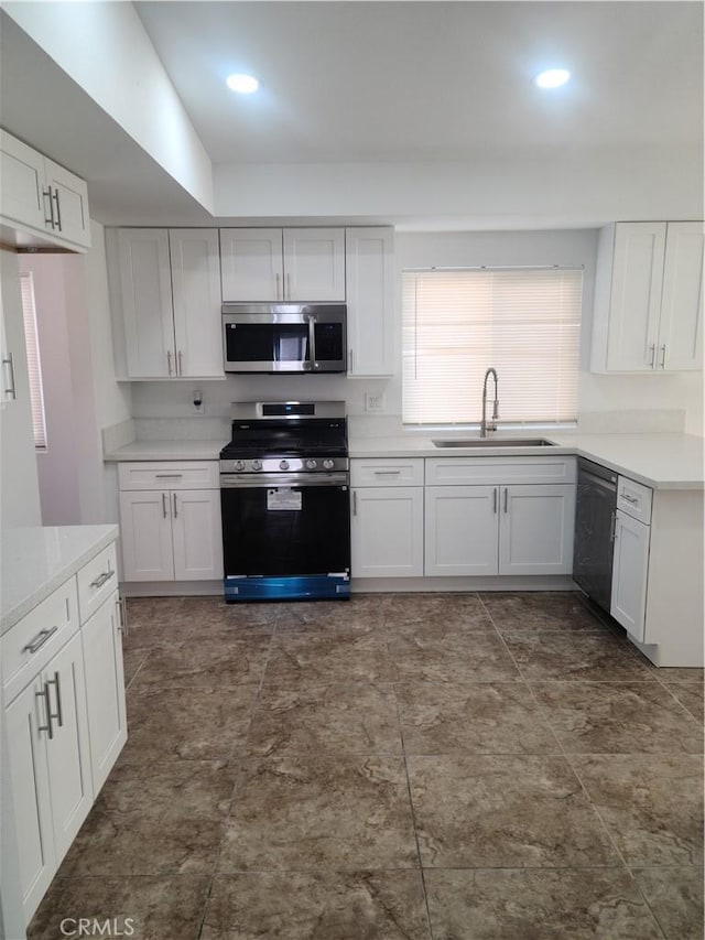 kitchen with white cabinets, appliances with stainless steel finishes, light countertops, and a sink