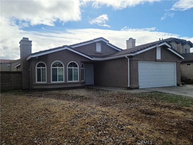 view of front facade with stucco siding, an attached garage, and a chimney