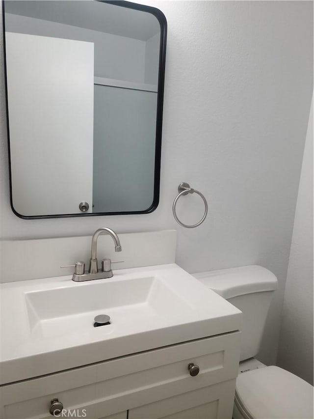 half bath featuring vanity and toilet