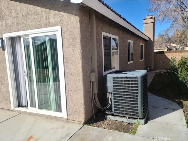 exterior details featuring fence, central AC, and stucco siding