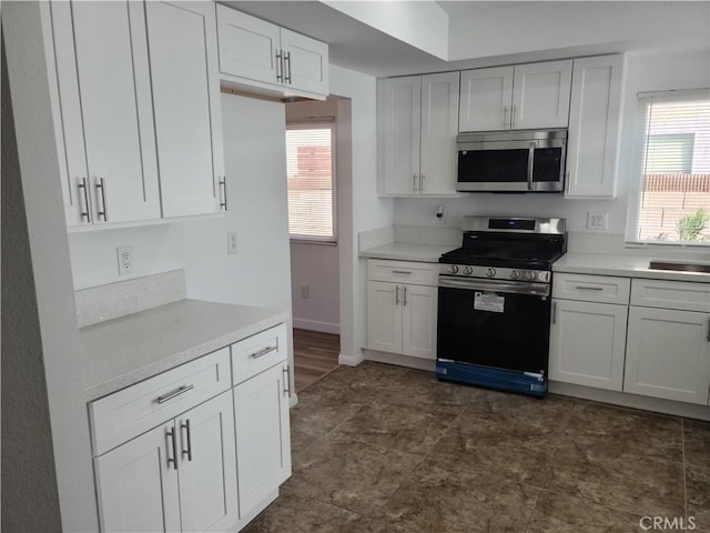 kitchen with white cabinetry, stainless steel appliances, and light countertops