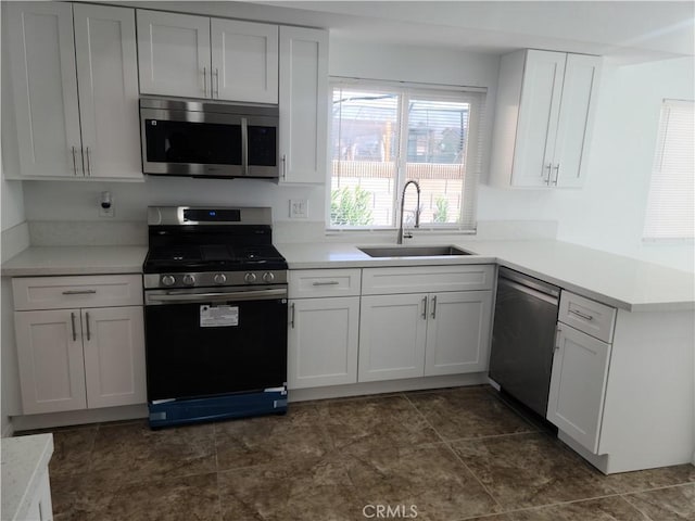 kitchen featuring a sink, a peninsula, light countertops, and stainless steel appliances