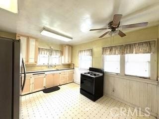 kitchen featuring light brown cabinetry, black range oven, light countertops, and freestanding refrigerator