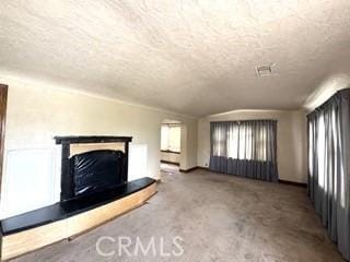 unfurnished living room featuring lofted ceiling, a fireplace with raised hearth, and a textured ceiling