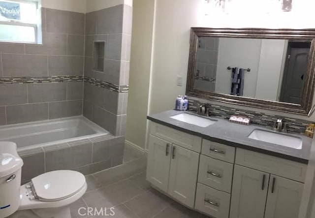 bathroom featuring a sink, backsplash, toilet, and tile patterned floors