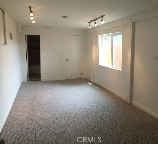 empty room with track lighting, light colored carpet, and baseboards