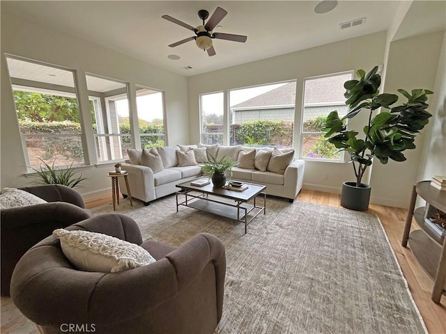 living room featuring visible vents, ceiling fan, light wood-type flooring, and baseboards