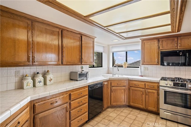 kitchen featuring tasteful backsplash, black appliances, brown cabinetry, and a sink