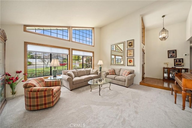 carpeted living room with a high ceiling and a chandelier