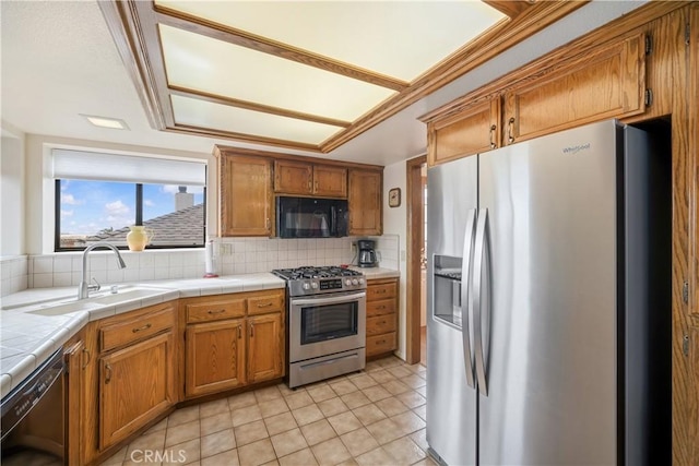 kitchen with decorative backsplash, black appliances, brown cabinets, and a sink