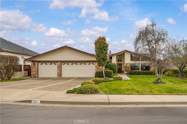 view of front of property with stone siding, an attached garage, concrete driveway, and a front yard