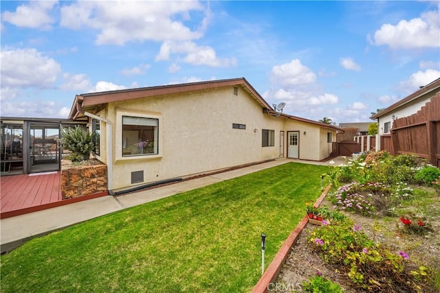 rear view of property with stucco siding, a lawn, a patio, and fence