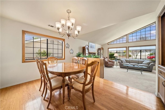 dining room with visible vents, baseboards, a chandelier, light wood-type flooring, and lofted ceiling