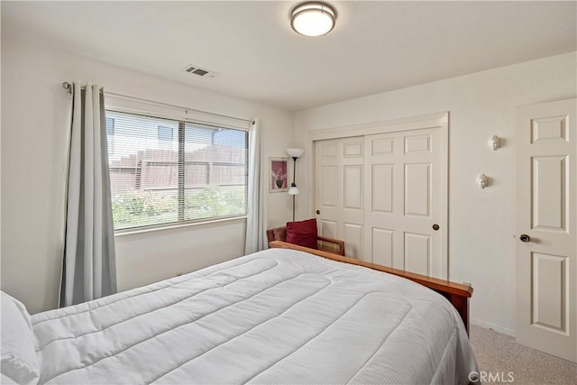 carpeted bedroom featuring a closet and visible vents