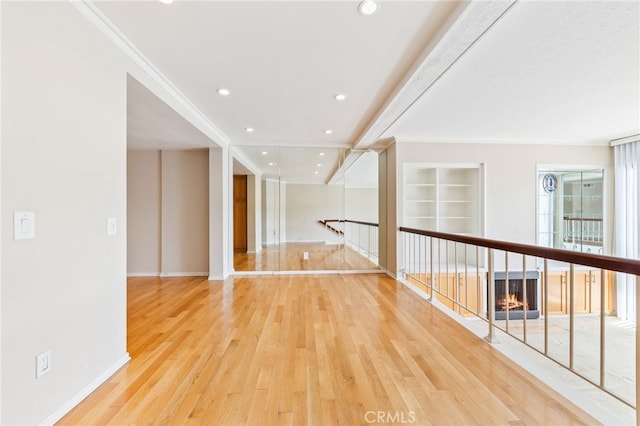 unfurnished room featuring built in features, wood finished floors, recessed lighting, crown molding, and a multi sided fireplace