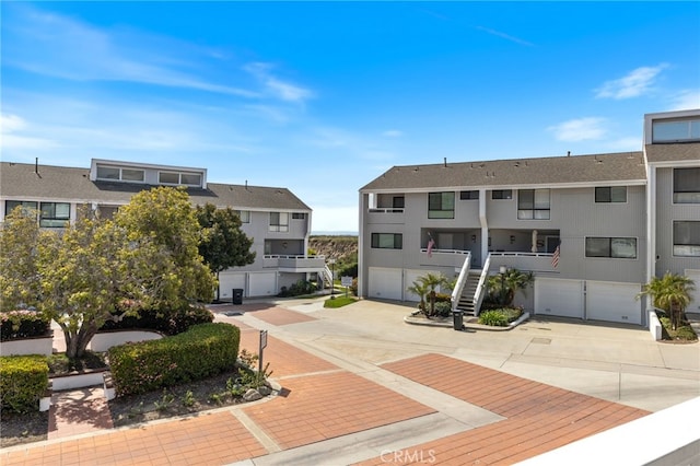 view of property's community with stairway, an attached garage, and driveway