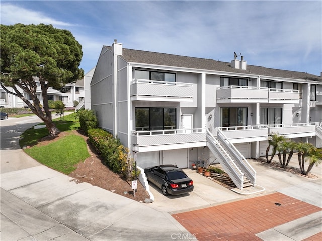 view of building exterior with stairway, driveway, and a garage