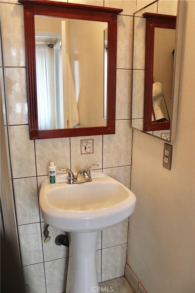 bathroom with a sink and tile walls