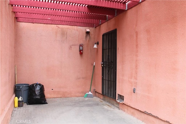 view of exterior entry with stucco siding and a pergola