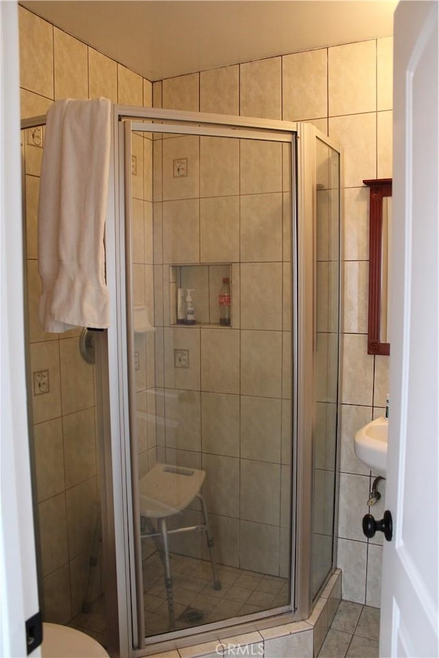 full bathroom featuring tile patterned floors, a shower stall, and tile walls