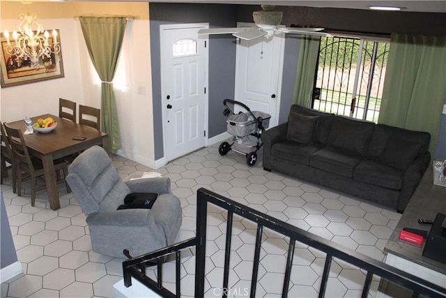 living area featuring ceiling fan with notable chandelier and baseboards