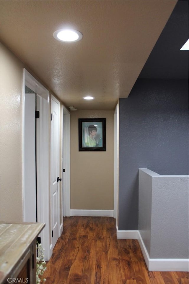 corridor featuring recessed lighting, wood finished floors, baseboards, and a textured ceiling