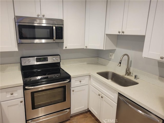 kitchen with a sink, stainless steel appliances, light countertops, and white cabinetry