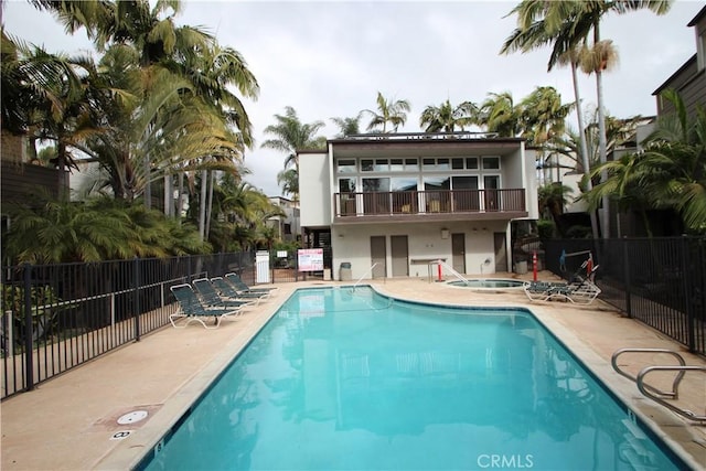 rear view of property with a patio area, a hot tub, a community pool, and fence