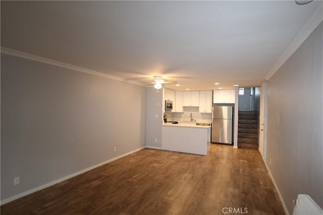 unfurnished living room with baseboards, dark wood finished floors, stairs, ornamental molding, and a sink