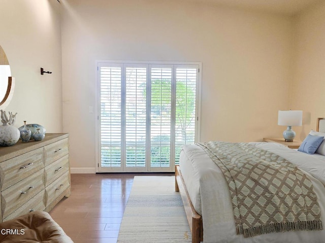 bedroom featuring access to exterior, baseboards, and wood finished floors