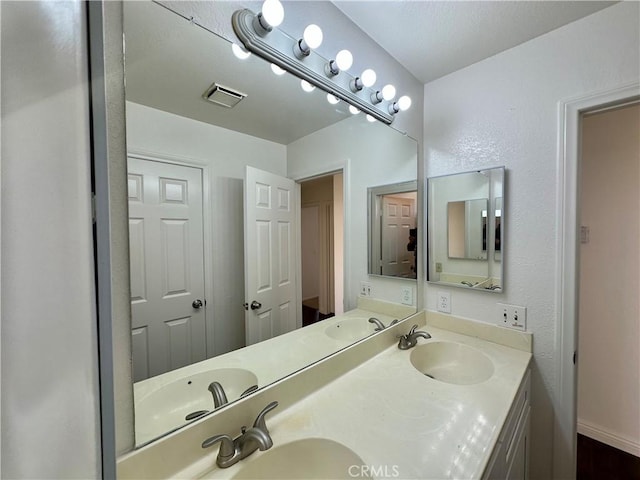 full bathroom featuring double vanity, visible vents, and a sink