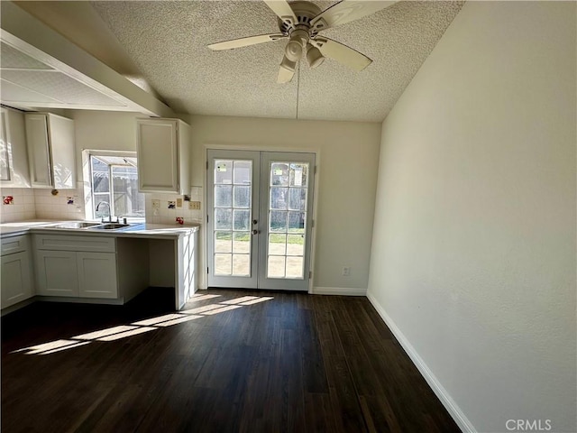 kitchen with baseboards, dark wood finished floors, a sink, french doors, and white cabinetry