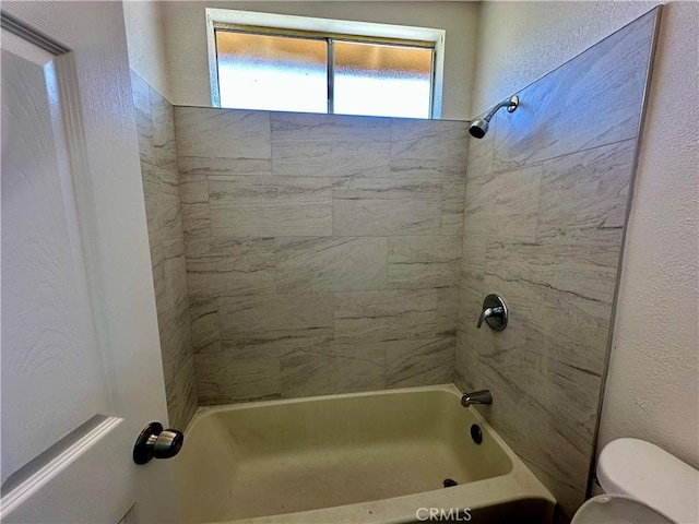 full bathroom featuring toilet, a textured wall, and shower / bathtub combination