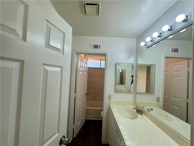 full bathroom with visible vents, a textured ceiling, and vanity