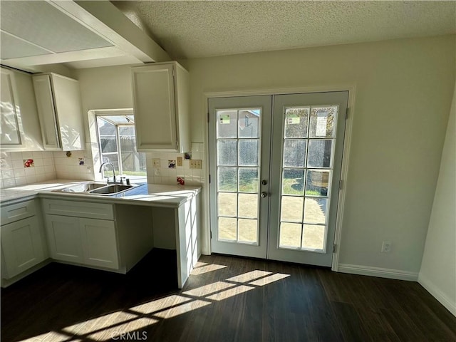 kitchen featuring dark wood finished floors, light countertops, french doors, and a sink