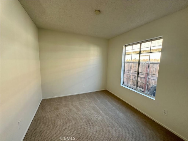 unfurnished room featuring carpet, baseboards, and a textured ceiling