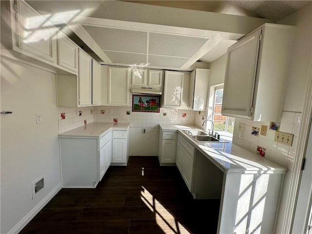 kitchen featuring a sink, visible vents, tasteful backsplash, and dark wood finished floors