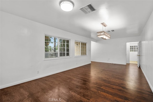 empty room with visible vents, baseboards, and dark wood-style flooring