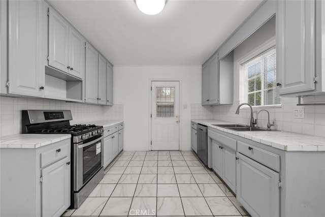 kitchen with a sink, stainless steel appliances, backsplash, and tile counters