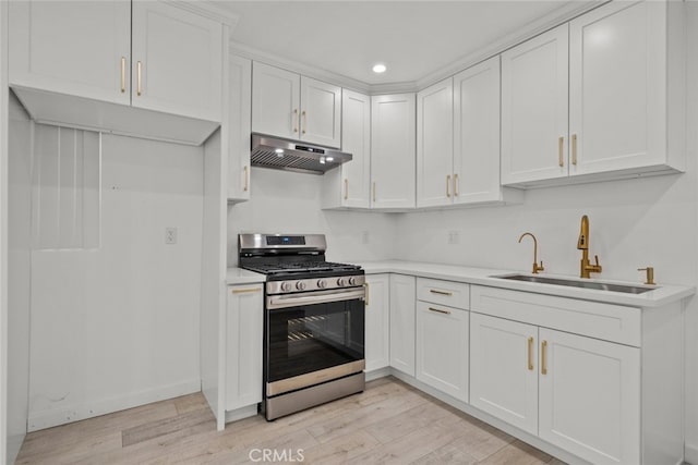 kitchen with stainless steel gas range oven, light countertops, under cabinet range hood, and a sink