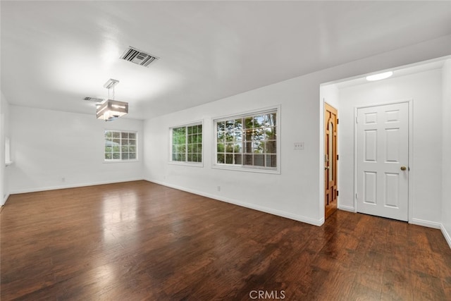 unfurnished room featuring visible vents, baseboards, and dark wood-style floors