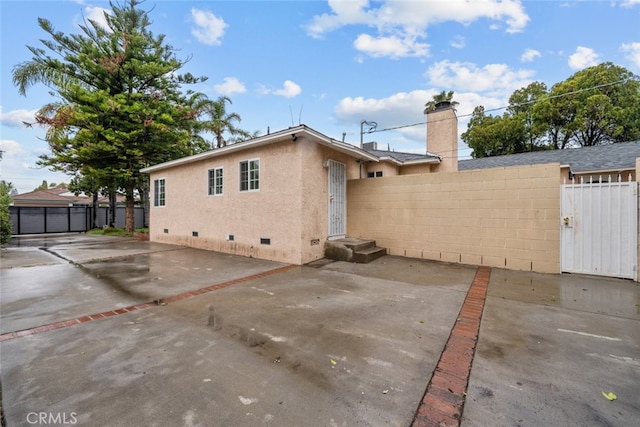 back of house with fence, a patio area, stucco siding, a chimney, and crawl space