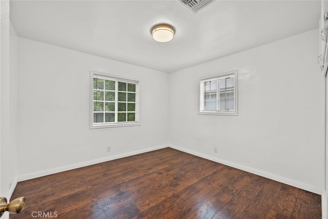 spare room featuring visible vents, baseboards, and dark wood finished floors