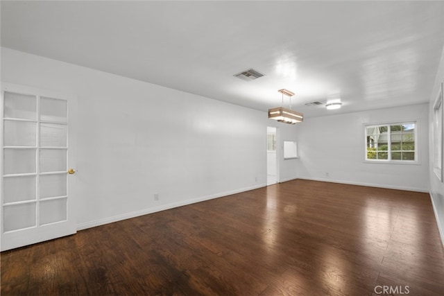 spare room with visible vents, baseboards, and wood finished floors