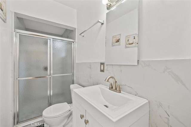 full bath with vanity, a shower stall, toilet, and tile walls