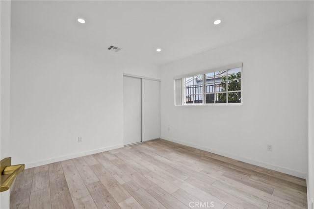 unfurnished bedroom with recessed lighting, visible vents, a closet, and wood finished floors