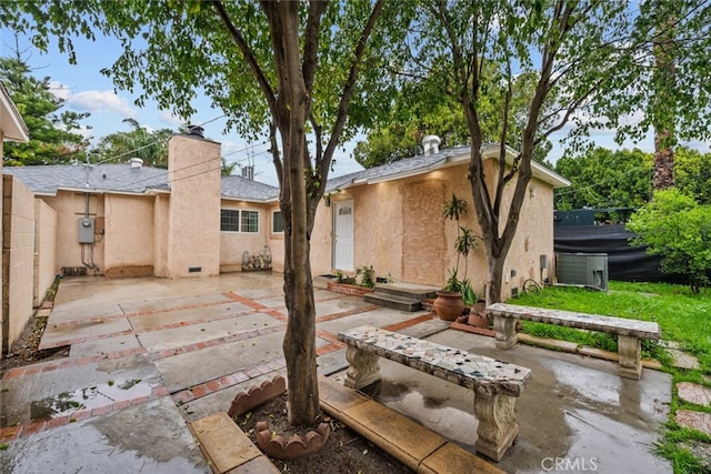 back of property featuring stucco siding, an outbuilding, fence, a chimney, and a patio area